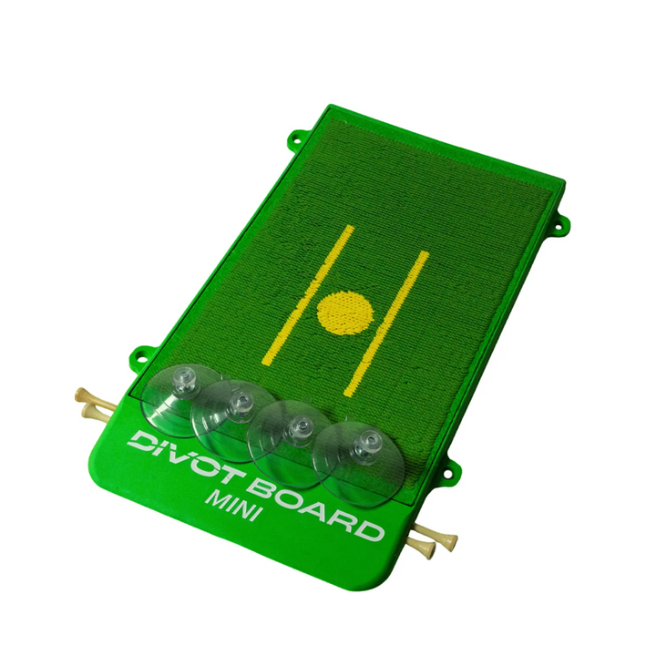 Divot Board MINI swing trainer at an angle, turf pad with yellow alignment lines, loose suction cups and tees